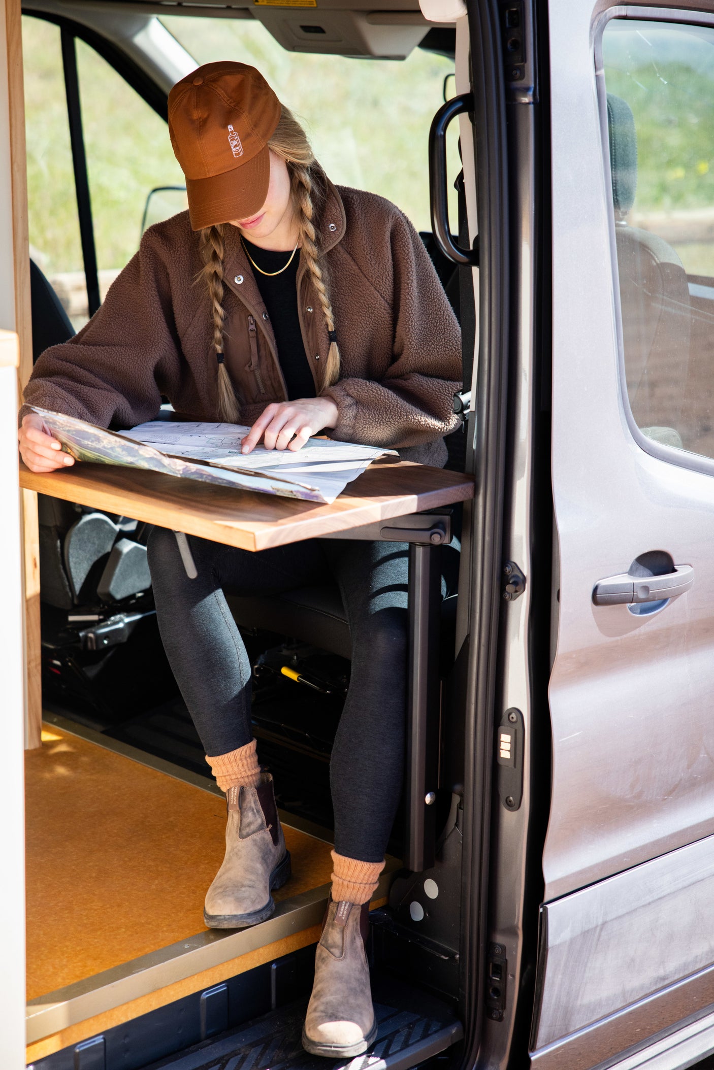 Planning your next adventure! Woman studies a map inside a cozy RV rental van, ready for the open road.