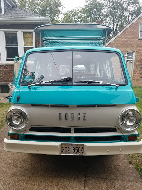 parked by trees. A classic option for an RV rental adventure.|Front view of a vibrant turquoise and white vintage Dodge pop-top camper van