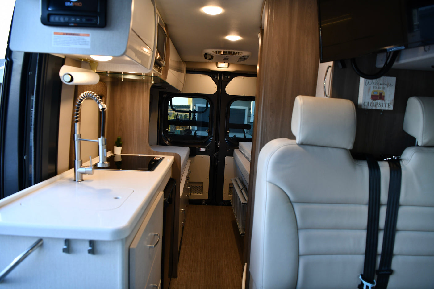 Modern rv rental interior with kitchen sink, comfortable seating, and a rear bed area, ready for your next adventure.