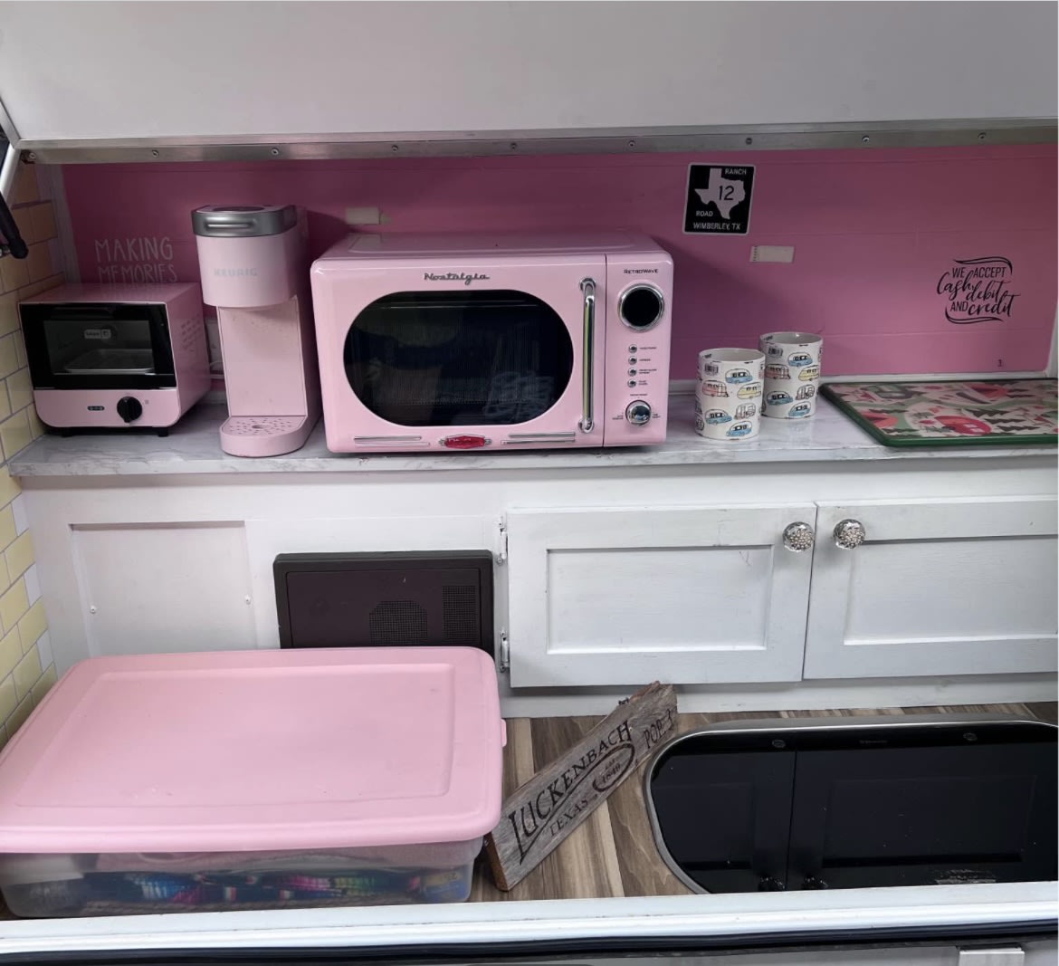 Cozy pink retro RV rental kitchen, featuring a microwave, Keurig, and toaster oven for making travel memories.
