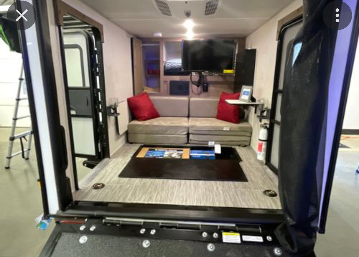 RV rental interior: versatile living space with convertible sofa, entertainment, and rear ramp access for gear.