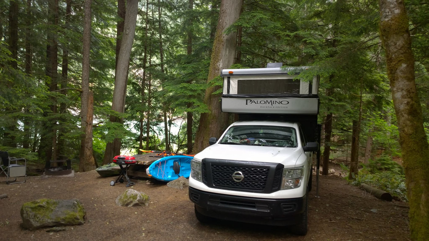 parked at a shopping center.|White truck with detached truck camper at an RV site