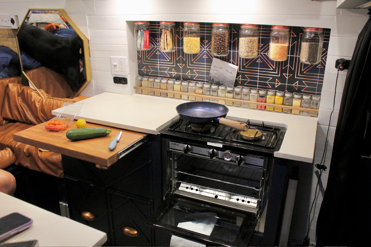 RV rental kitchen: compact stove/oven, pull-out prep board, and organized food/spice storage for travel.