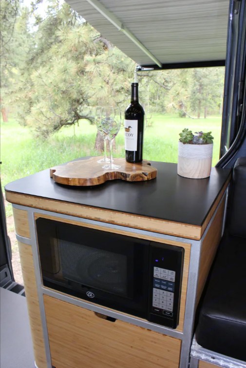 RV rental: Stylish kitchenette with wine, glasses, microwave, and a succulent, offering scenic outdoor views. — photo 3