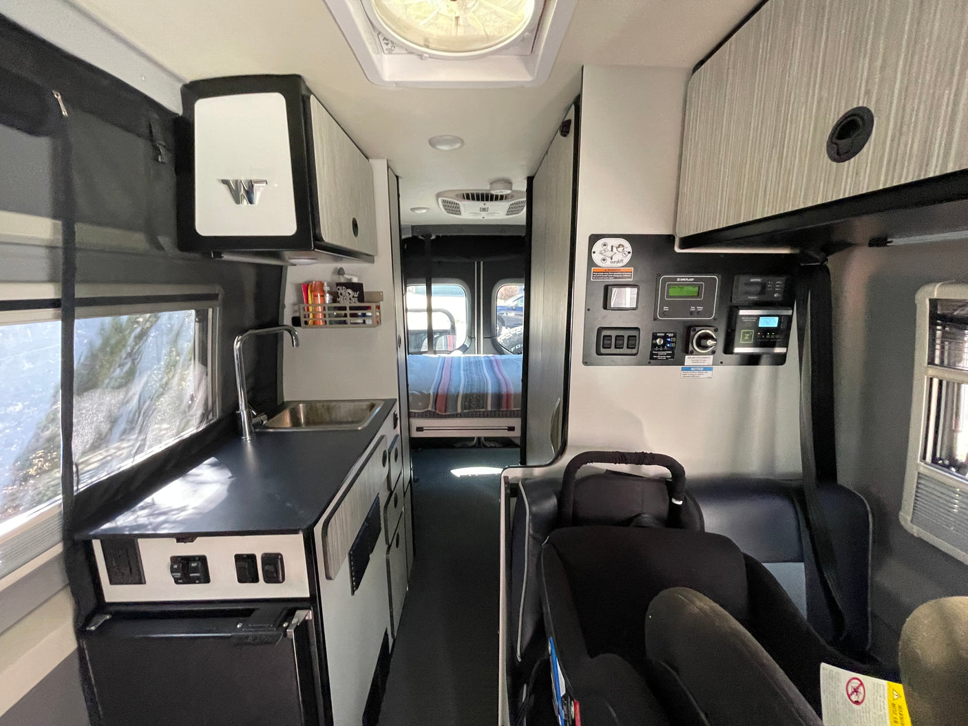 RV rental interior: kitchenette, control panel, child seat, and rear bed visible. Perfect for family travels.