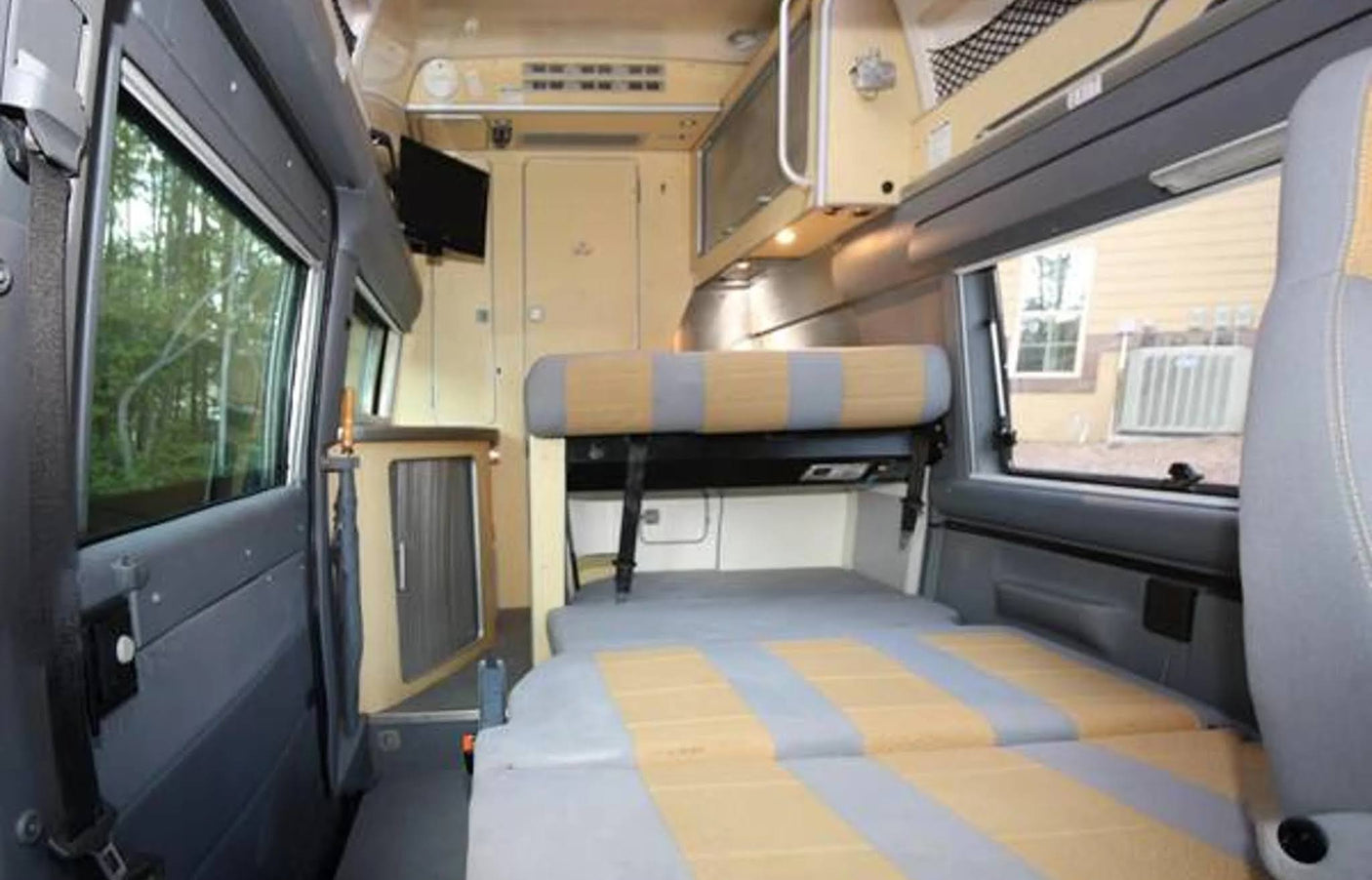 Explore this cozy RV rental interior with its flexible seating, convertible bed, compact kitchen, and scenic windows.