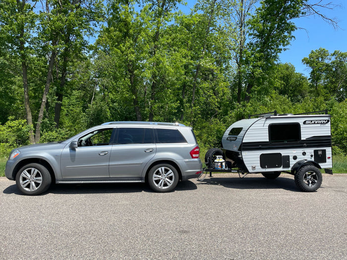 an ideal RV rental for off-road adventures.|A silver SUV tows a grey Sunray Sport compact travel trailer RV