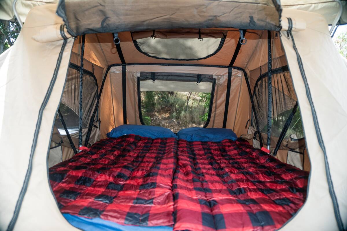 showing a dark mattress and stunning ocean view. Ideal for an RV rental adventure!|Cozy interior of a rooftop tent