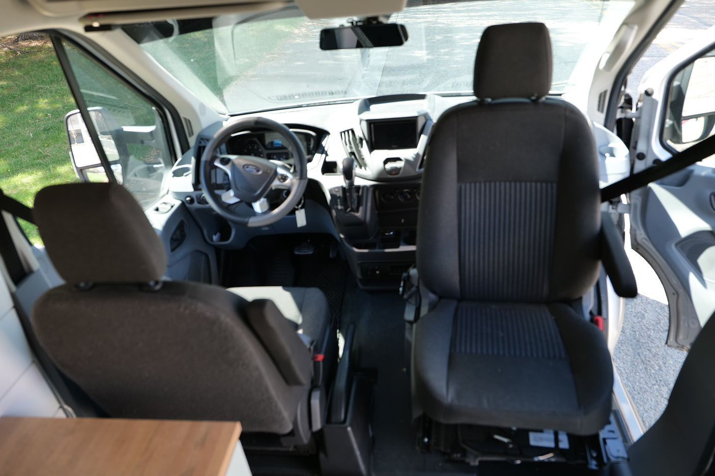 View inside an RV rental van: front cabin with driver's and passenger seats, dashboard, and Ford steering wheel.