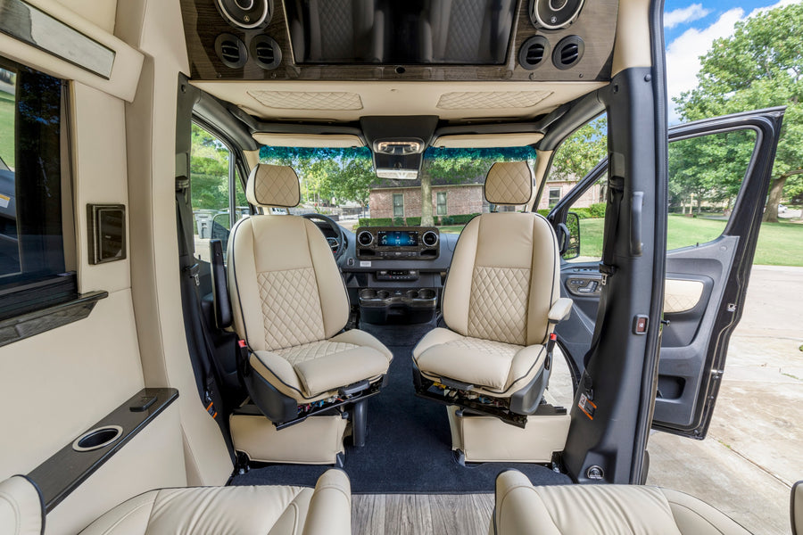 Luxurious RV rental interior, showing swivel front seats & dashboard, offering comfort & style.