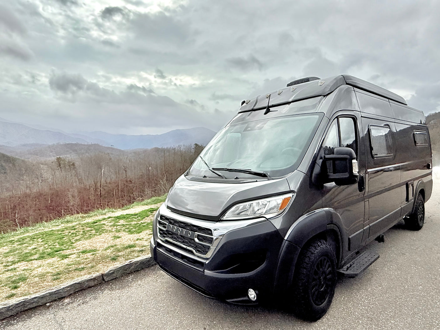 Experience freedom with an RV rental! Modern VW camper van with pop-top roof, parked on a sunlit gravel path, ready for adventure.