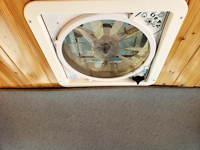 RV rental comfort: Overhead ceiling fan with adjustable controls and protective screen for optimal air circulation.