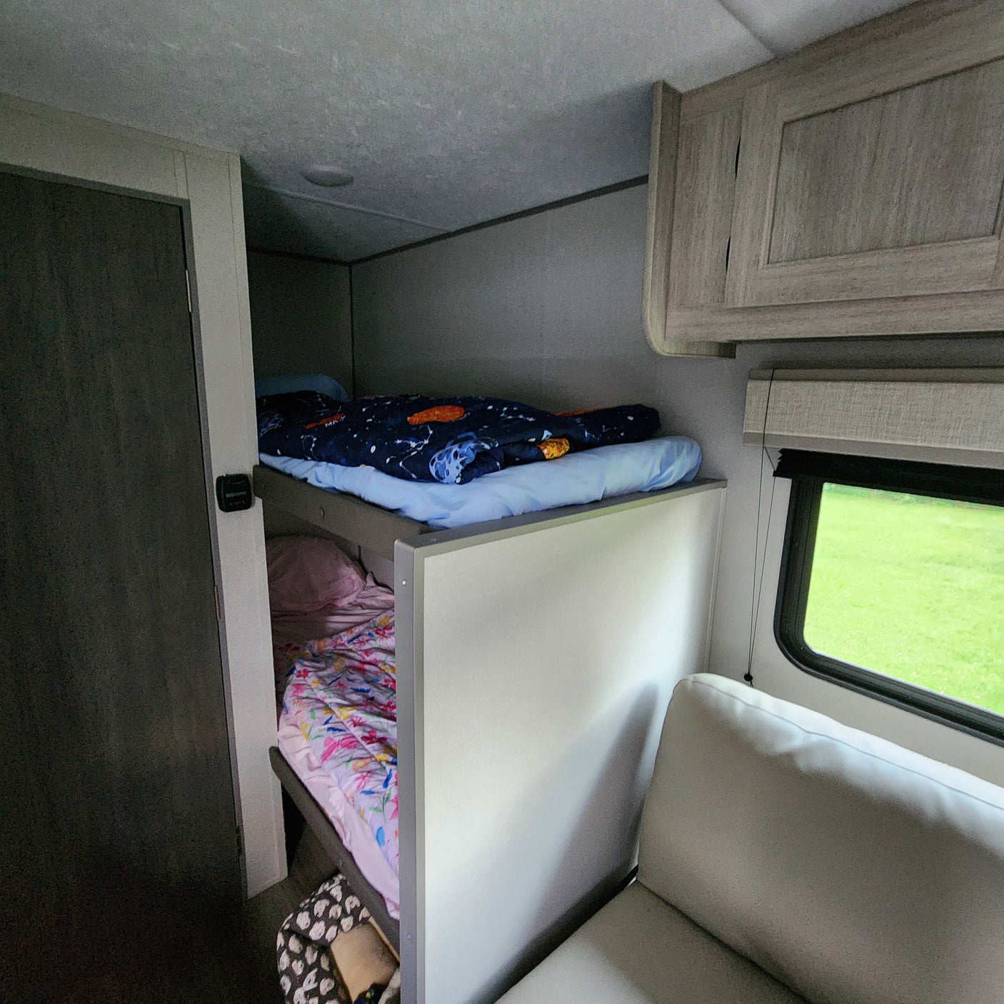 Inside an rv rental: comfortable bunk beds with colorful bedding and an exterior view from the window.