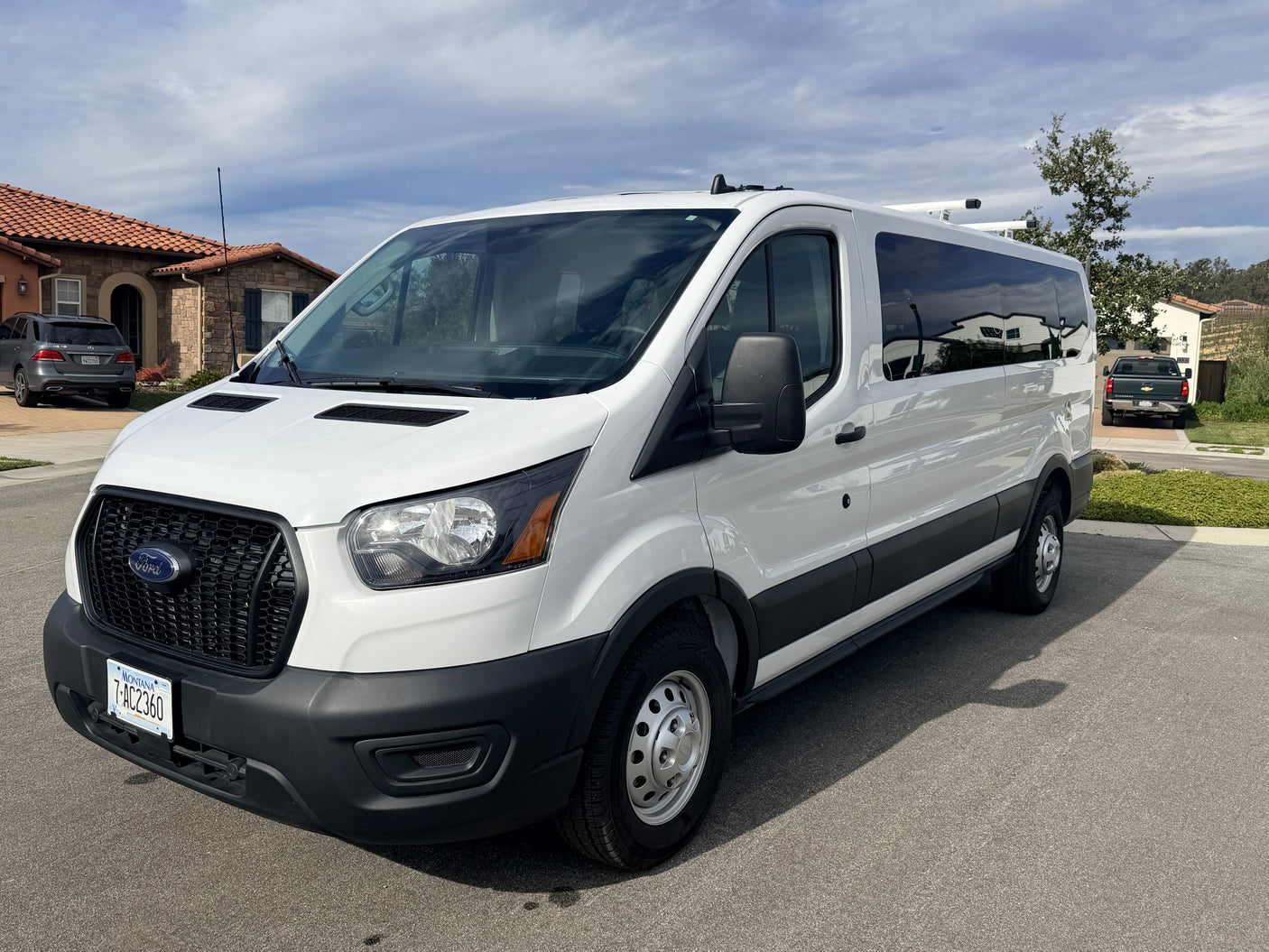 White Ford Transit van, suitable for an RV rental or commercial use, parked on a street. Montana plates visible.