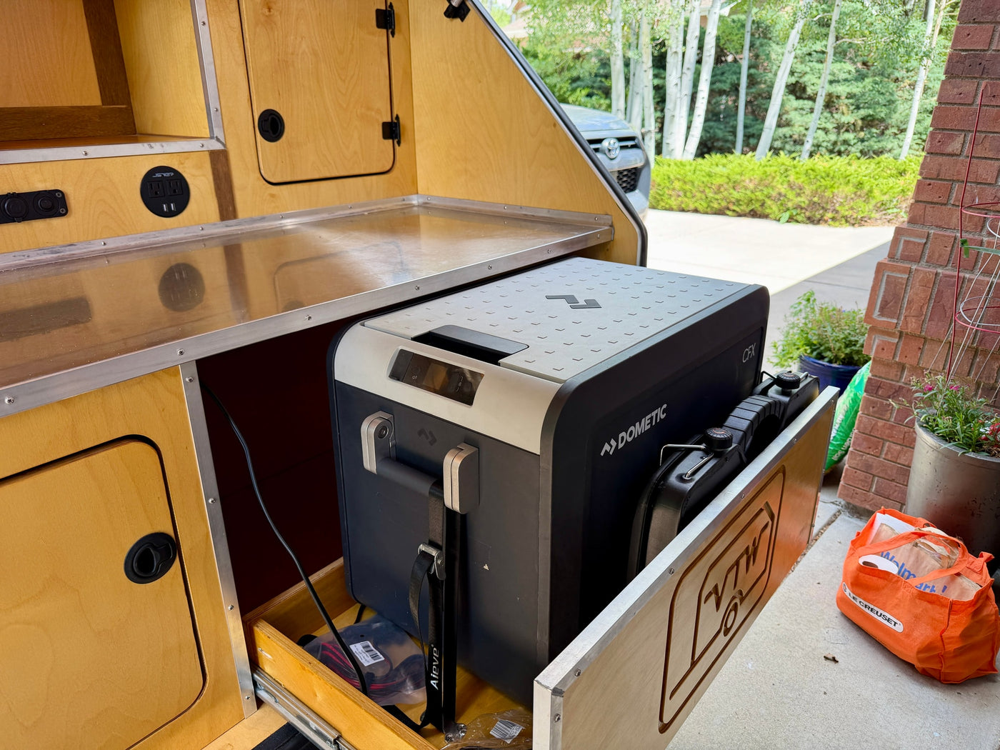 Teardrop RV rental kitchenette: Dometic fridge on slide-out, stainless counter, power & USB outlets. — photo 7