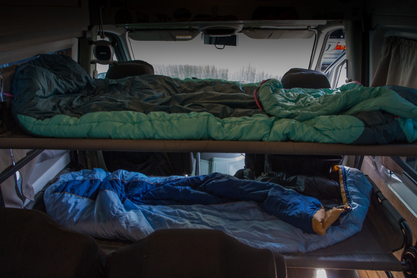 Cozy RV rental interior with bunk beds, featuring sleeping bags on top and bottom bunks for comfortable travel.
