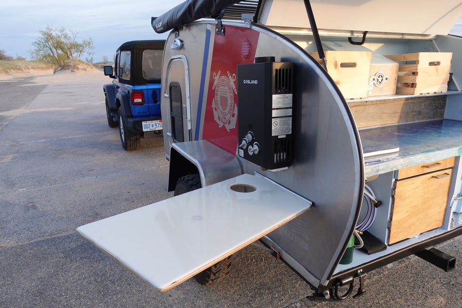 An rv rental teardrop trailer with a Coast Guard theme and an outdoor kitchen, ready for adventure with a Jeep.