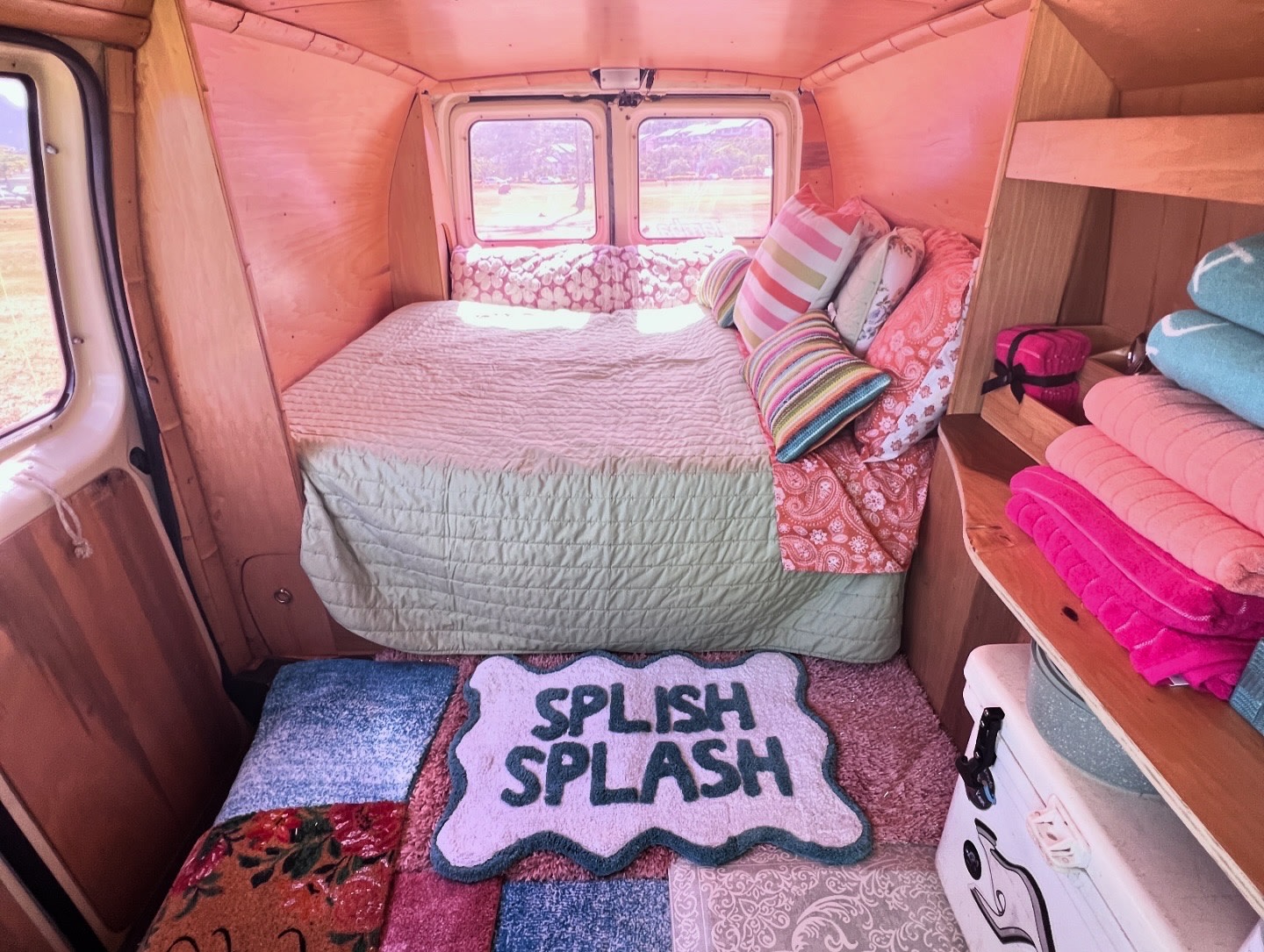 Explore this charming rv rental's interior: a comfy bed, pink walls, colorful towels, and a fun "Splish Splash" mat.