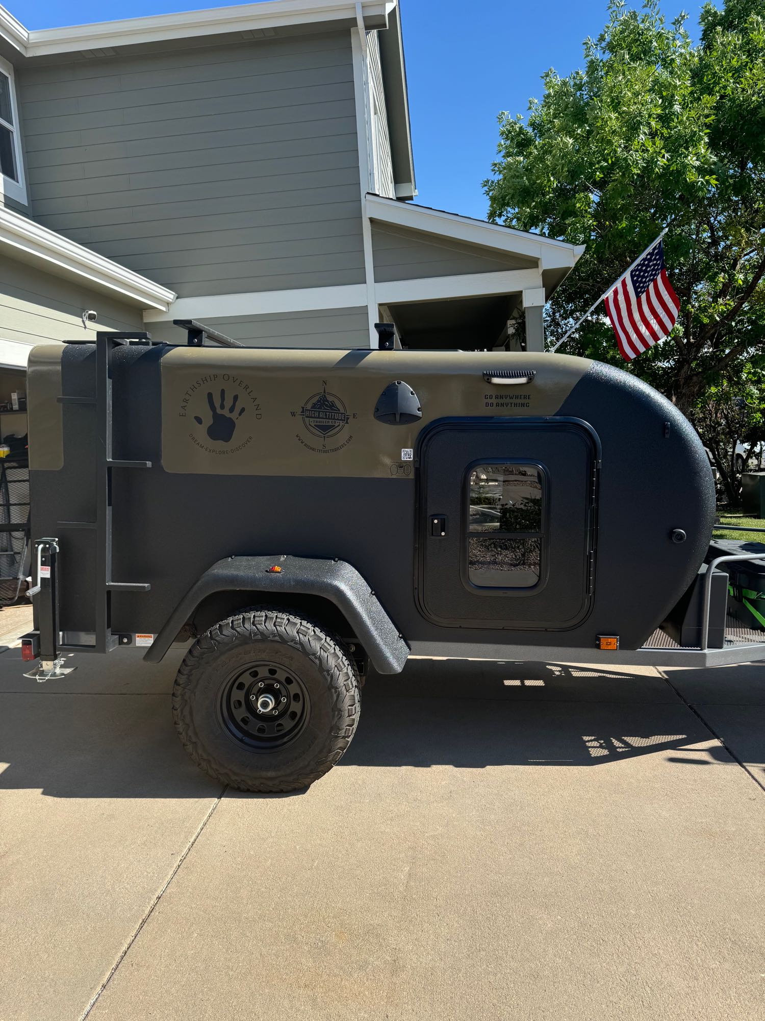 and an open door leading to an inviting patio.|This rugged Earthship Overland teardrop trailer from High Altitude is ready for adventure! Ideal for an RV rental getaway.|This rugged Earthship Overland off-road RV rental is parked on a driveway