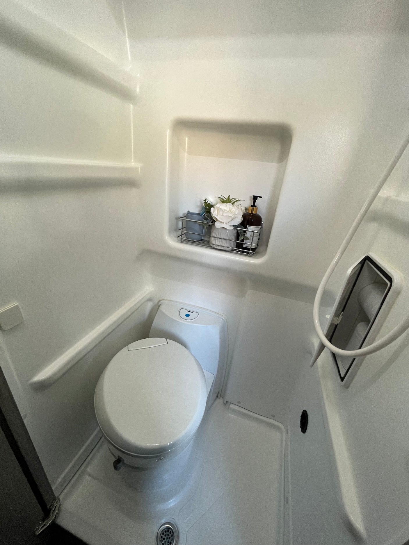 This RV rental wet bath offers a compact toilet, shower, and integrated shelf with toiletries.