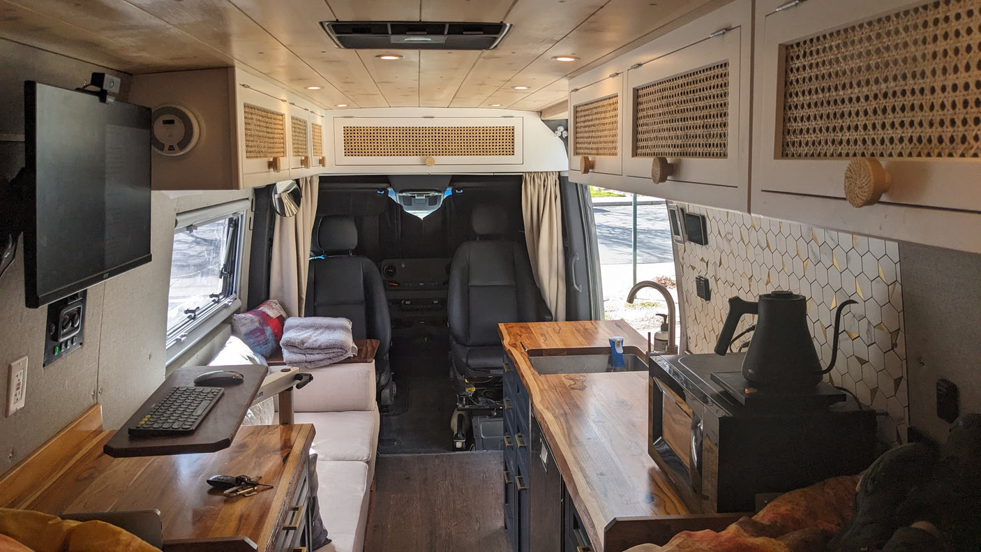 RV rental van interior with a bright, custom-built design. Features a wood-paneled ceiling, modern kitchen, and cozy living area.