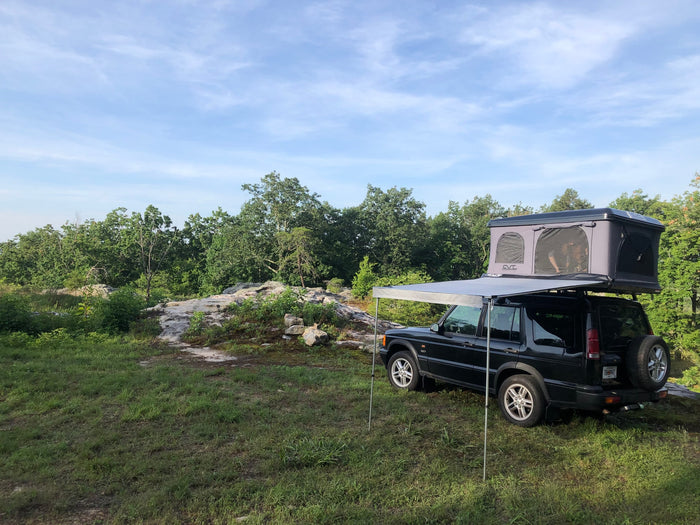 perfect for an rv rental adventure.|Black Land Rover Discovery with an open rooftop tent & awning setup. Great RV rental alternative for overlanding and camping.|Black SUV with a rooftop tent and awning
