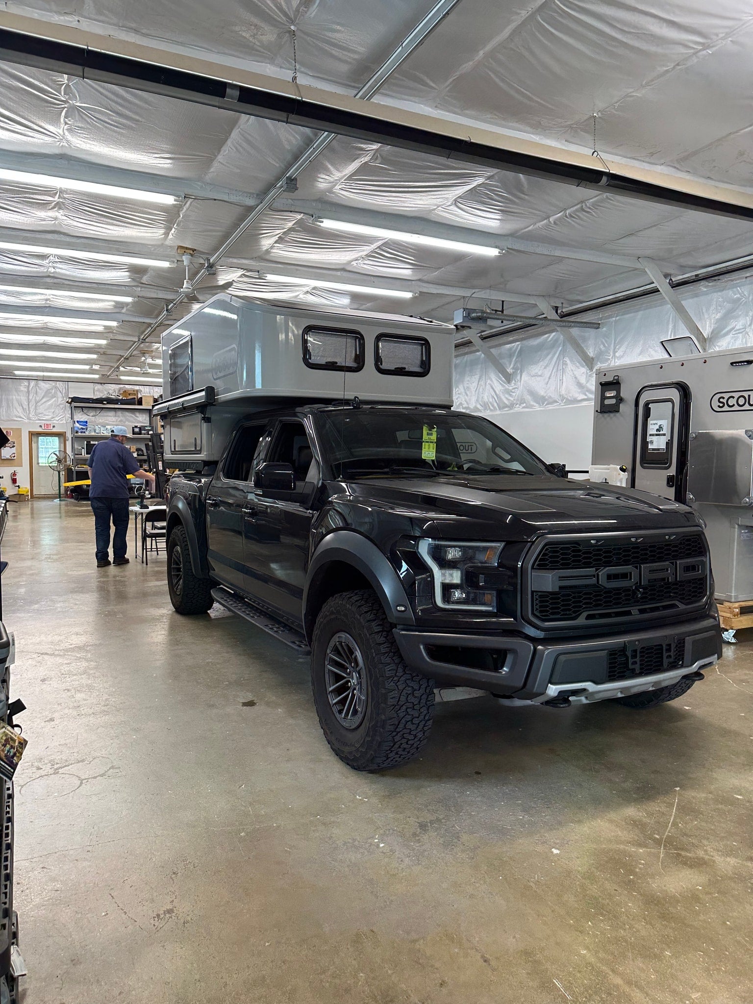 A black Ford Raptor with a Scout truck camper, adventure-ready for your next RV rental journey.
