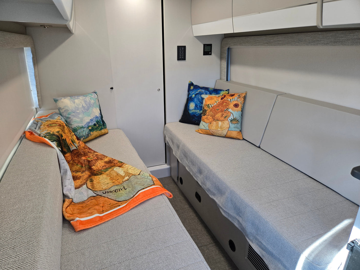 Cozy RV rental interior with stylish bench seating, Van Gogh art pillows, and a vibrant throw blanket for a comfortable stay.