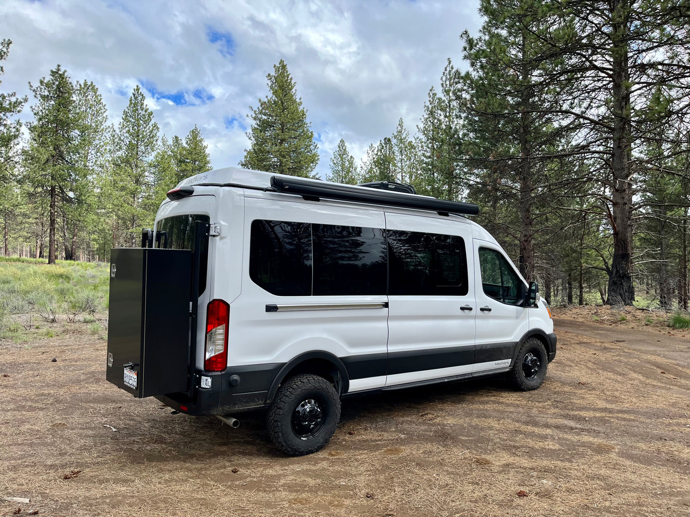 White custom camper van, ready for your next rv rental outdoor adventure in a serene pine forest.