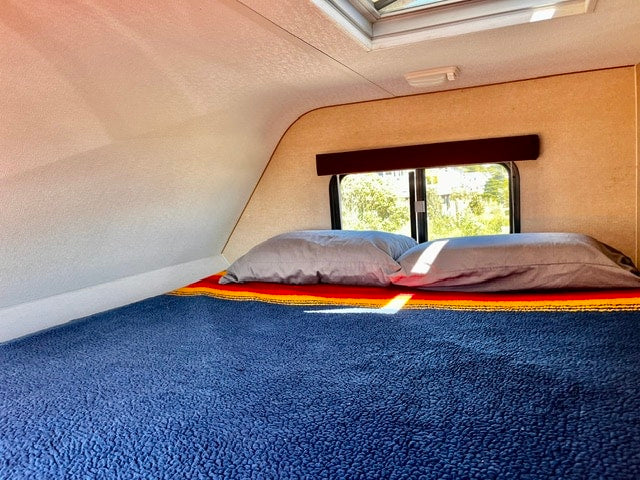 with a scenic view through the window. Perfect for RV travel.|RV rental refrigerator: A wood-paneled fridge with a top control panel inside an RV. Ideal for compact living.|RV rental control unit on a textured wall: ON/OFF switch