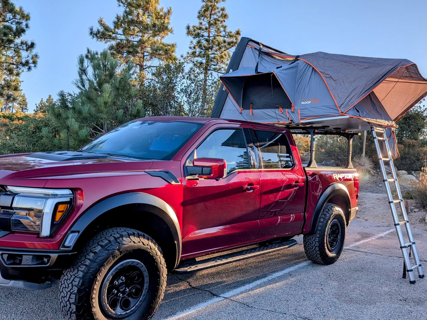 Red Ford Raptor truck with a deployed roof-top tent — photo 1