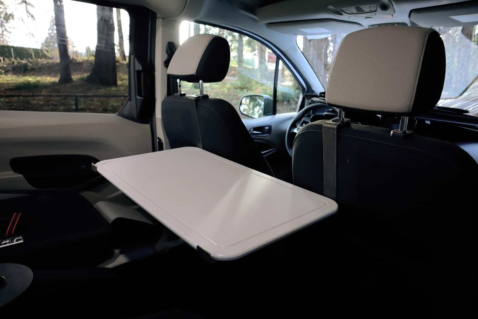 RV rental interior: A white tray table, perfect for mobile work or dining, extends from the front passenger seat back.