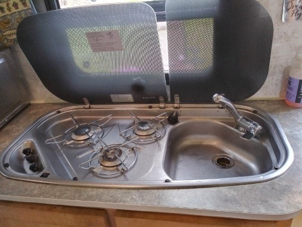 with a compact kitchen and storage for comfortable travel.|RV rental's compact wet bath with toilet