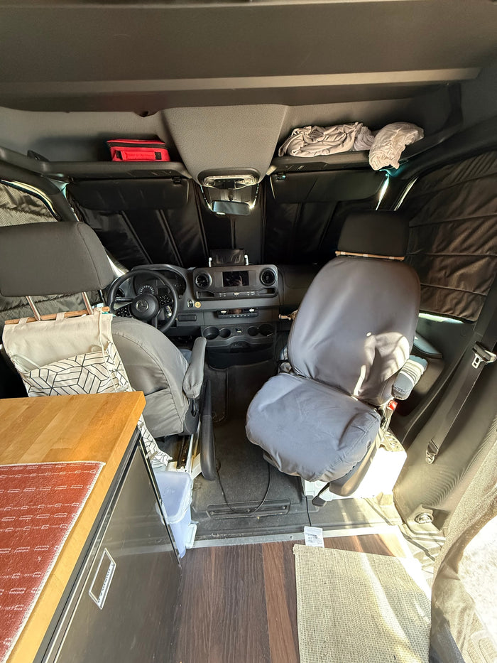 with chairs set up for a scenic waterfront relaxation.|RV rental camper van with rooftop cargo