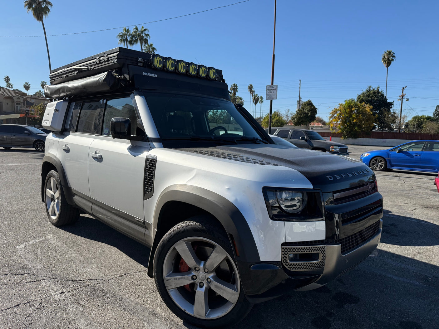 This rugged Land Rover Defender, outfitted with a rooftop tent & KC lights, is perfect for an rv rental outdoor adventure.