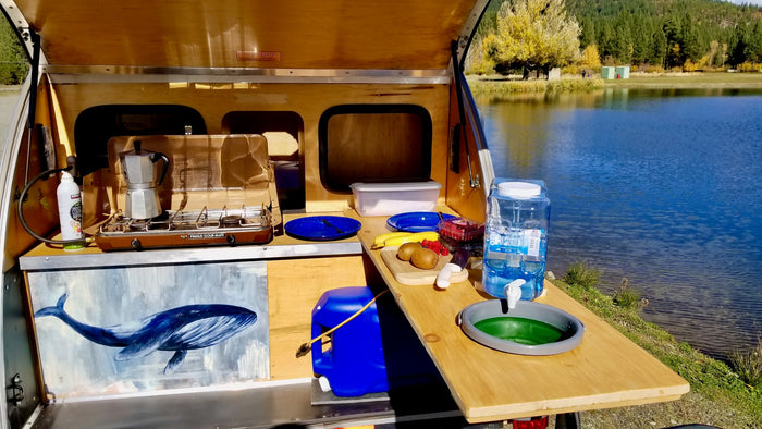 perfect for camping & biking adventures.|Lakeside cooking setup: A woman preps food at a teardrop RV rental