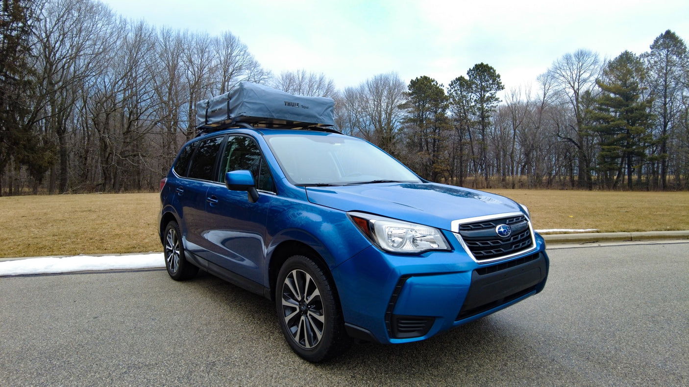 Blue Subaru Forester SUV with Thule rooftop tent, an ideal alternative to RV rental for outdoor adventures & camping.