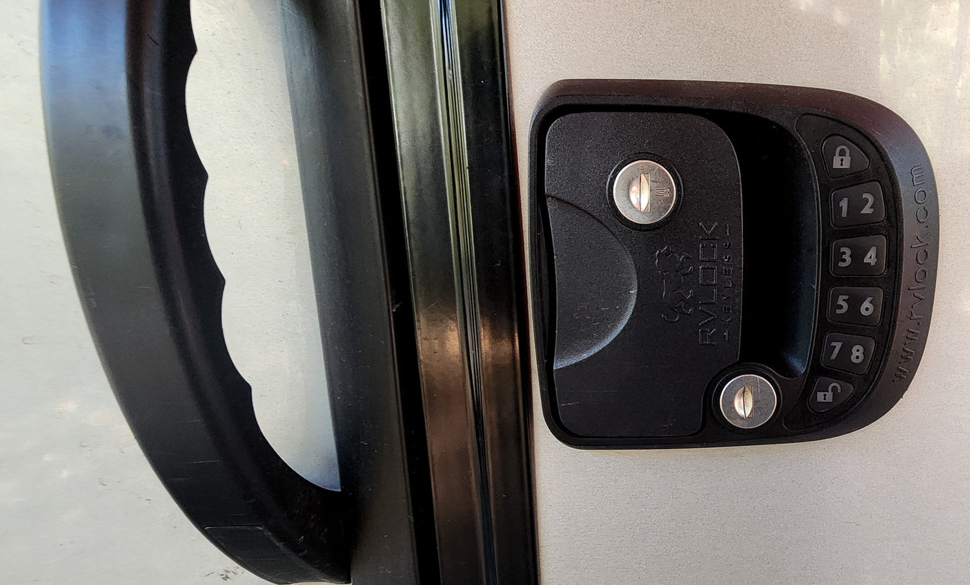 RV rental door with black handle & RVLOCK keyless keypad for secure entry. Two keyholes visible.