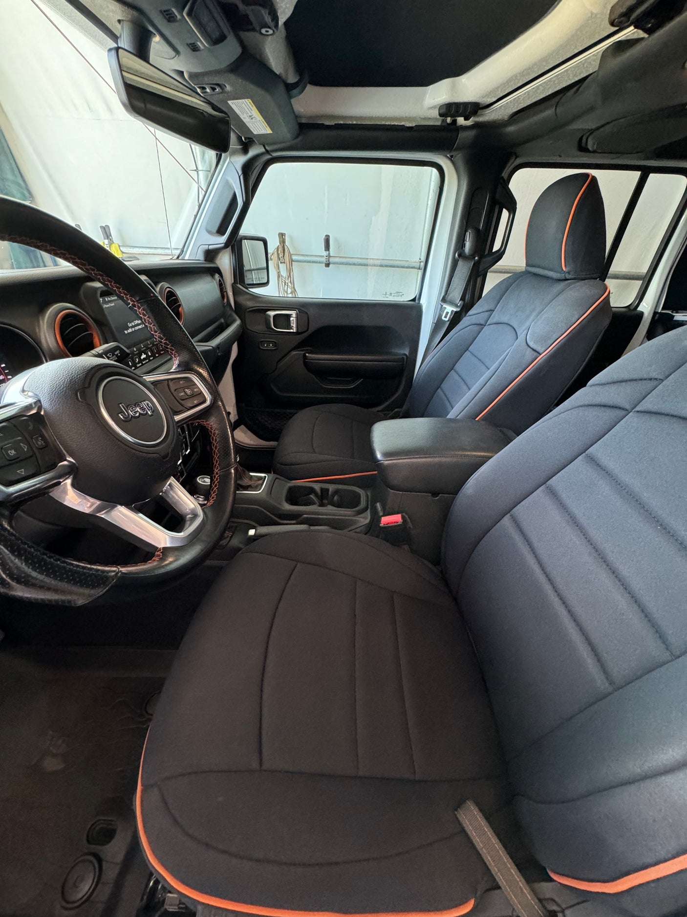 Inside a Jeep: black/orange custom seats, steering wheel, and dash visible. Consider this robust option for your rv rental needs.