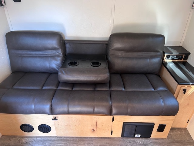 and a brown sofa.|Kids relax with books in a cozy rv rental interior. This modern travel trailer features comfy seating and amenities for travel.|This rv rental features a compact kitchen (sink