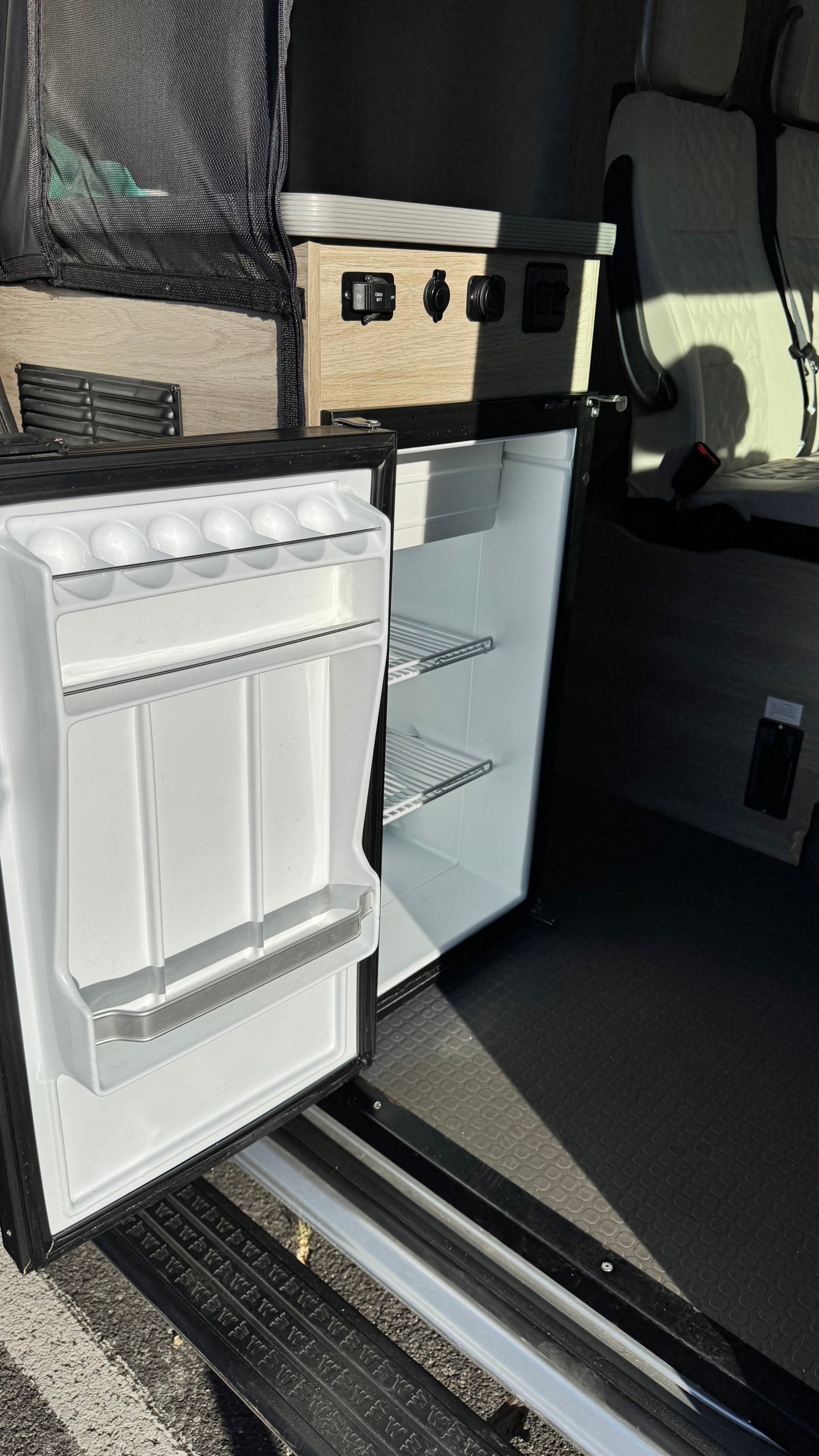 This RV rental features a convenient, open mini-fridge, visible power outlets, and comfortable seating for your road trip comfort.