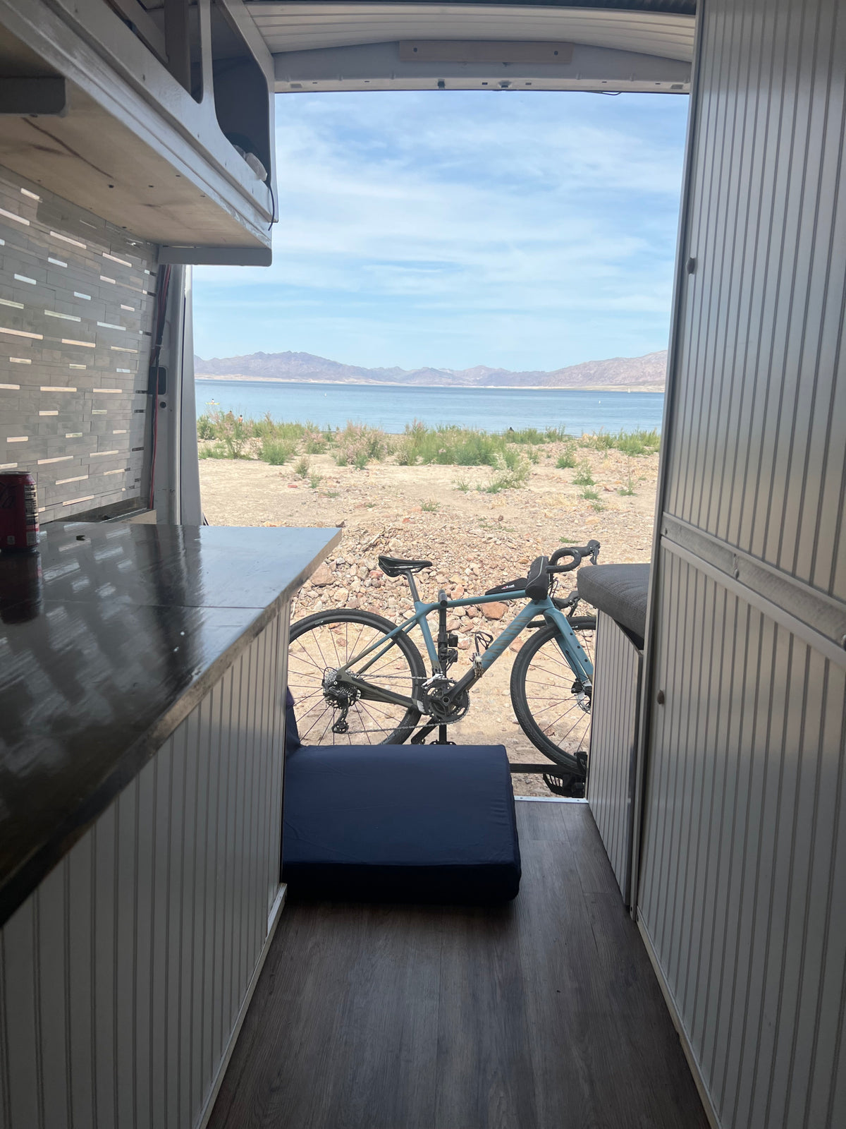 Inside an RV rental van: kitchen counter, bike storage, and stunning lake and mountain views await.