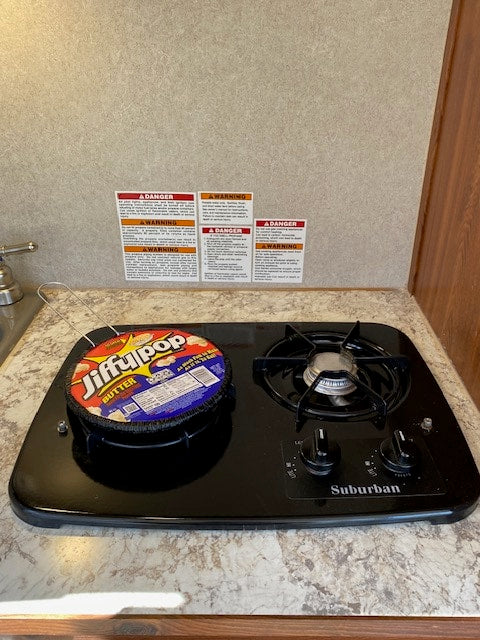 Jiffy Pop popcorn sits on a compact Suburban stove inside an RV rental. Ready for a cozy night in.