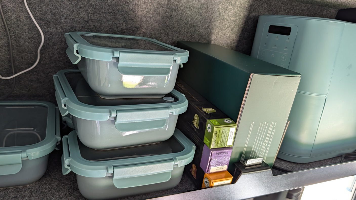 RV rental kitchen: Stacked meal prep containers, coffee pods, and a compact appliance neatly organized for travel.
