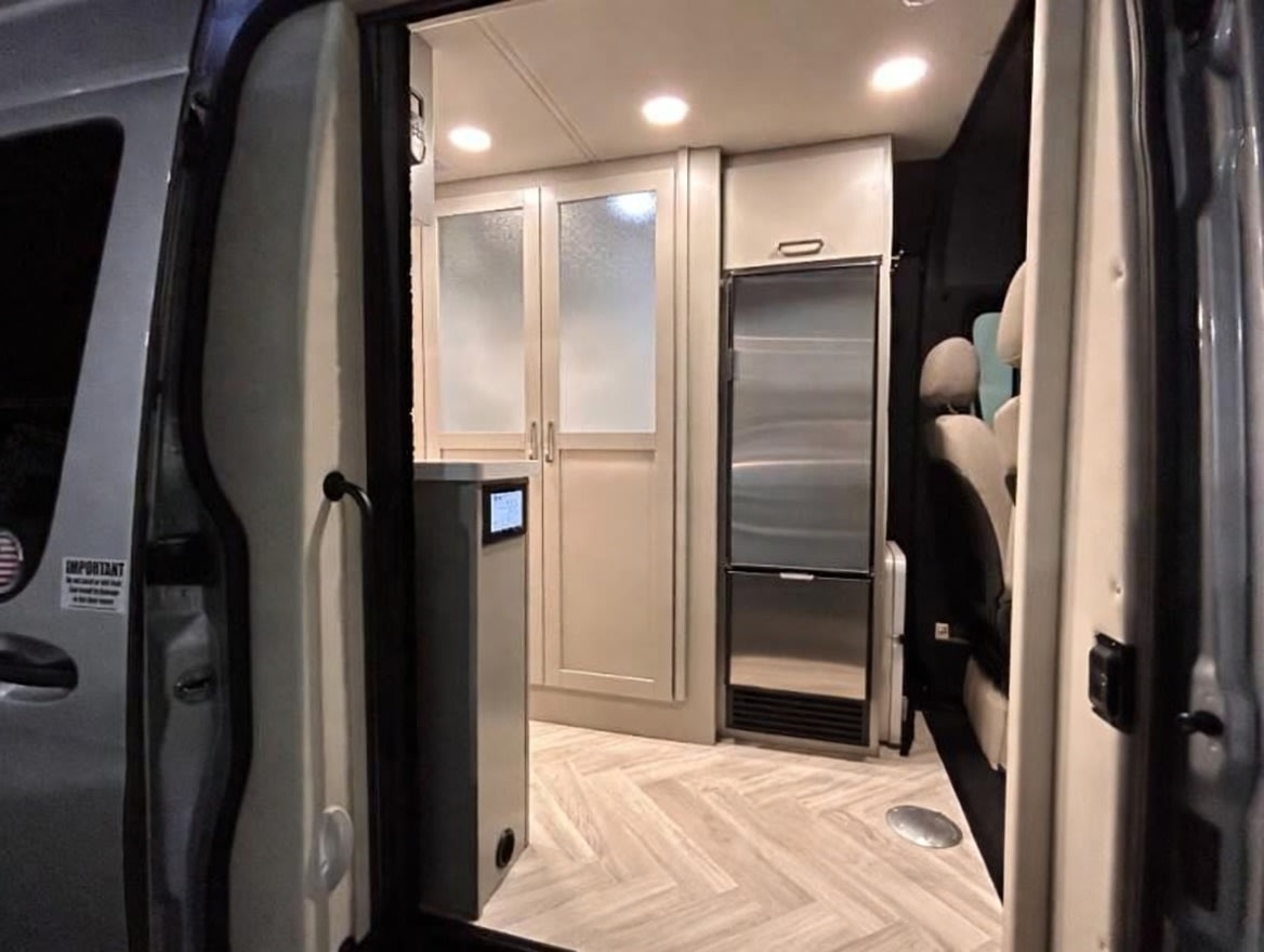 and comfy swivel seats.|Modern RV rental interior showing a narrow galley kitchen with sink