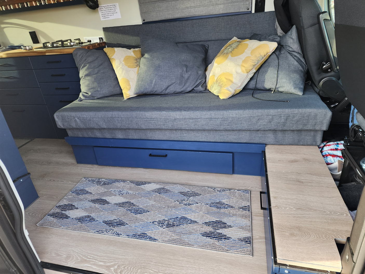 Cozy RV rental interior with blue sofa, kitchen, and smart drawer storage. Ideal for adventures.