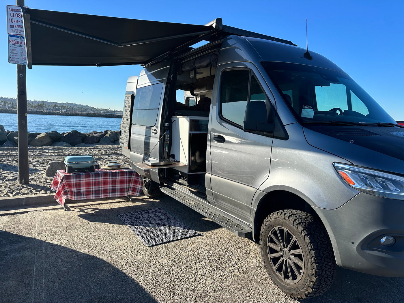 Gray rv rental van with awning deployed, featuring an outdoor kitchen and grill for beachside cooking and relaxation. — photo 6