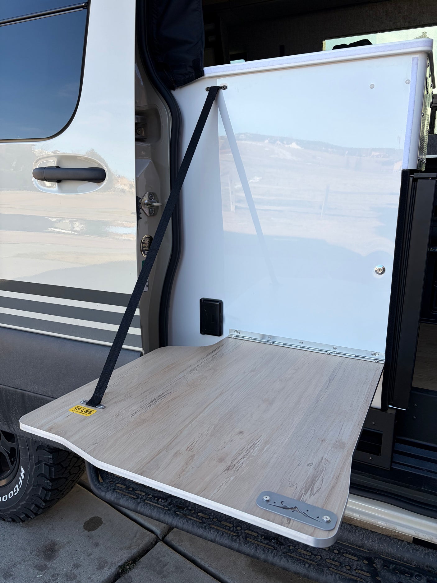 A handy fold-down table extends from this rv rental's side, supported by a strap, showing its 15 lbs capacity for outdoor use.