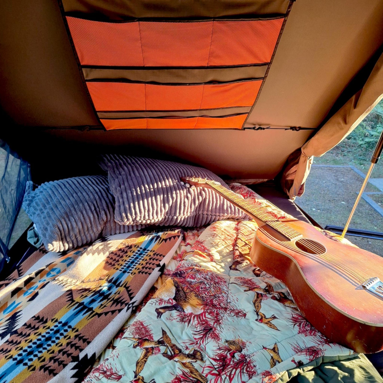 glowing lamp & 'Camp Destroyer' sticker on the back of an Oregon rv rental vehicle.|Black FJ Cruiser with rooftop tent & ladder for camping. Your next outdoor rv rental adventure awaits in nature.|Cozy rooftop tent setup in an RV rental
