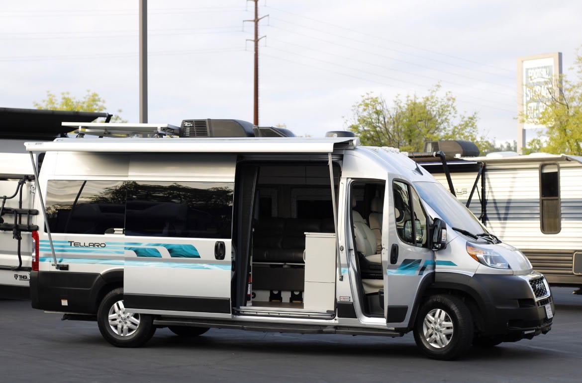 Silver Tellaro camper van with an open side door and extended awning, showcasing its interior for your next RV rental. — photo 2